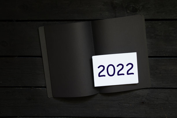 黑色木桌上的白色纸张笔记本和2022年文字，新年快乐图片下载