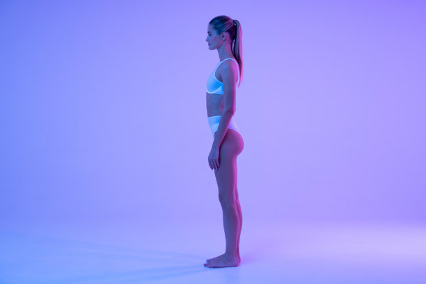 侧面视图在霓虹灯适合赤脚女人在内衣站在墙上的拷贝空间图片下载