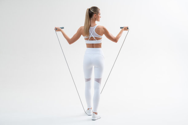 完整长度合身的女孩在白色运动服持有跳绳对白色背景图片下载