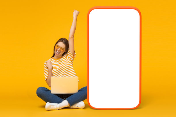 戴墨镜的女孩尖叫着，是的，把手举起来，坐在笔记本电脑旁边的大手机模型图片下载