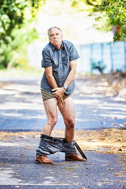 一名男子发现自己的裤子掉在了郊外的一条路上，尴尬地把自己盖了起来图片下载