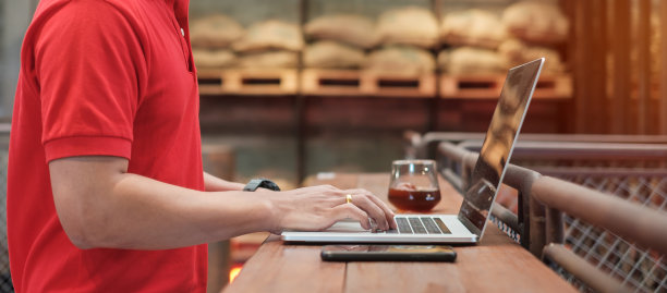 休闲商人使用智能手机和笔记本电脑，自由职业者打字笔记本电脑的键盘在咖啡馆或现代办公室。技术、数字在线和网络概念图片下载