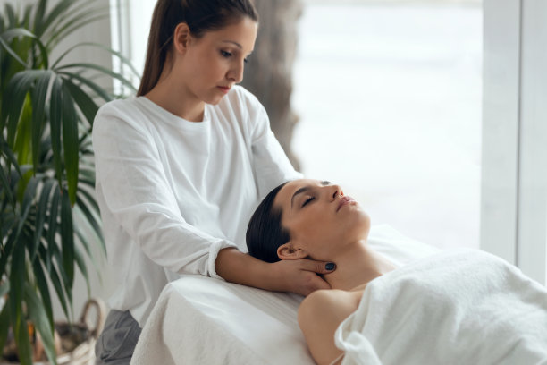 在水疗中心，美容师躺在担架上给美女做放松按摩。图片下载