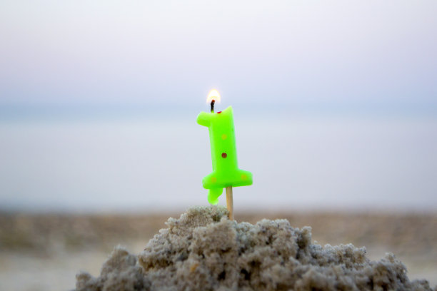 1号蜡烛插在沙子上燃烧。点燃的蜡烛图片下载