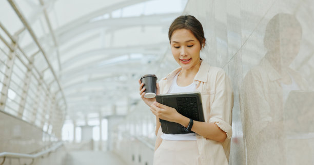 亚洲女商人在上班的路上用蓝牙耳机开会，脸上带着幸福的微笑。妇女使用城市交通路线免费的互联网技术在城市图片下载
