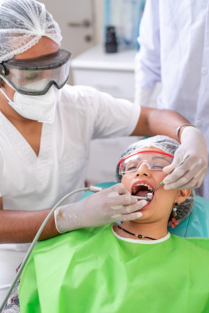 牙科医生用电子设备清洁病人的口腔图片下载