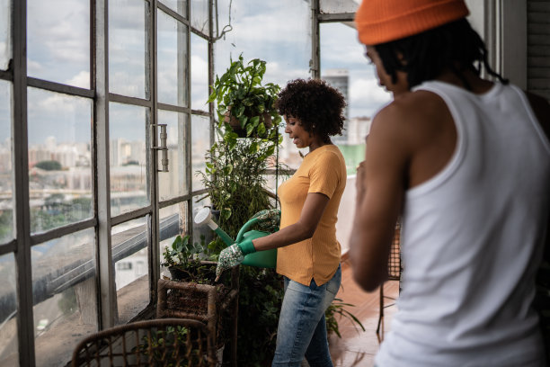 年轻人在家用手机拍摄女友浇花图片下载