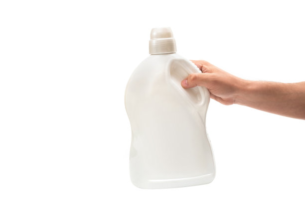 一只手拿着一瓶洗涤剂，背景是白色的。清洗的概念图片下载