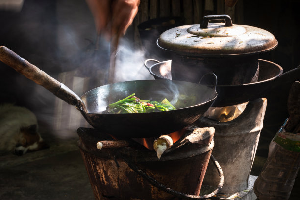 男人在老式炉子上用柴火煎锅烹饪蔬菜图片下载