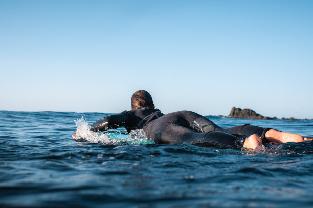 冲浪女孩从后面看。在水里的木板上划水图片下载