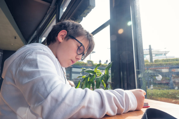 一个男孩正在咖啡馆的窗边看书图片下载