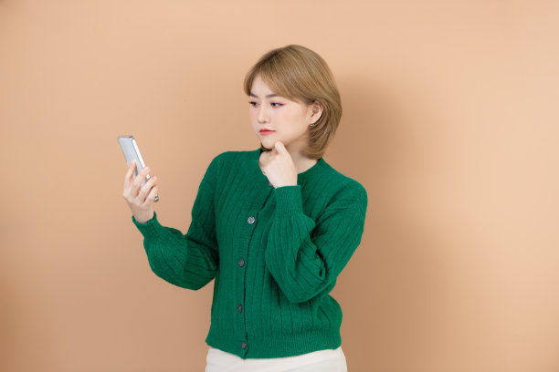 悲伤的女人正盯着米色背景的手机思考着什么问题图片下载