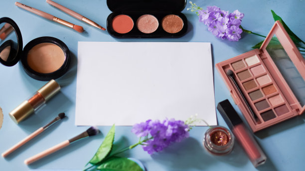 高级照片|平铺收集的美容产品在蓝色背景与空白的白纸图片下载