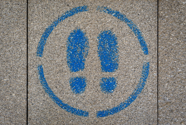 人行道喷漆标志显示两个蓝色的脚在一个圆圈内。图片下载