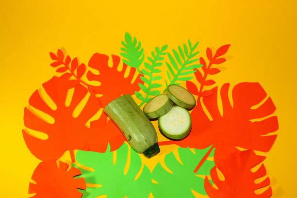 半个西葫芦和几片抽象的彩色叶子，创造性的夏季概念，热带设计图片下载