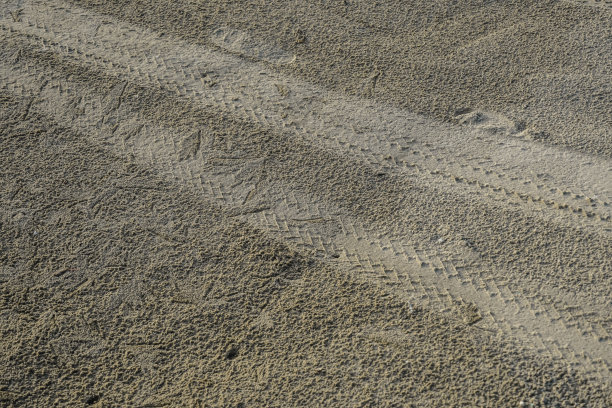 废弃的沙滩上的汽车轮胎印。图片下载