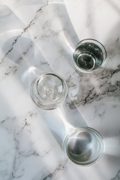 阳光透过水玻璃，在白色背景上通过光的折射，形成美丽的光影图案。图片下载