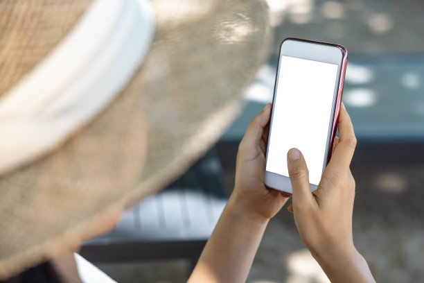 特写亚洲女人的手握和指着智能手机在海边晒太阳。网上购物、社交、科技、交流。剪切路径在白屏隔离图片下载