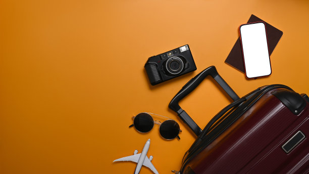 行李箱，智能手机，墨镜，相机和黄色背景的暑假护照。前视图。图片下载