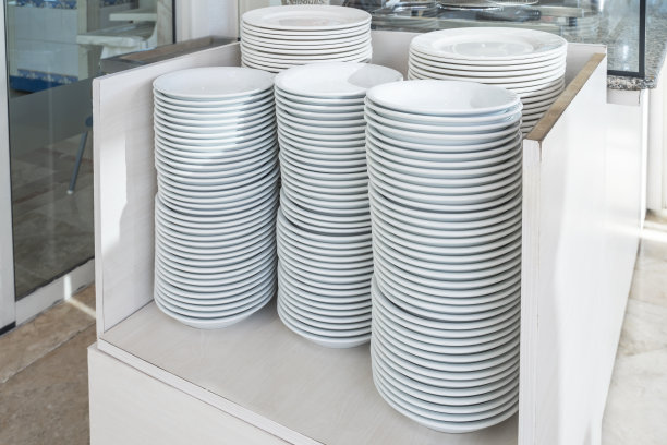 餐具，一套白色的盘子，盘子和杯子在自助餐餐厅的桌子上。高质量的照片图片下载
