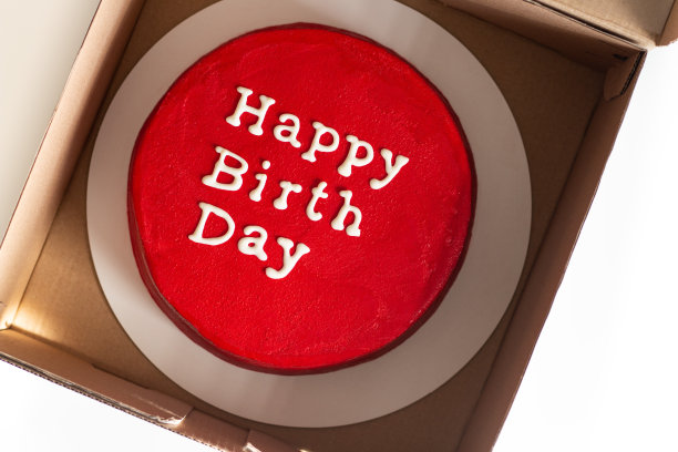 生日蛋糕，上面用红色孤立的字母。红色的圆形生日蛋糕，上面写着祝生日快乐图片下载