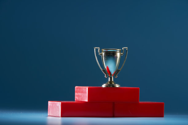 蓝色背景下红色领奖台上的金色奖杯图片下载