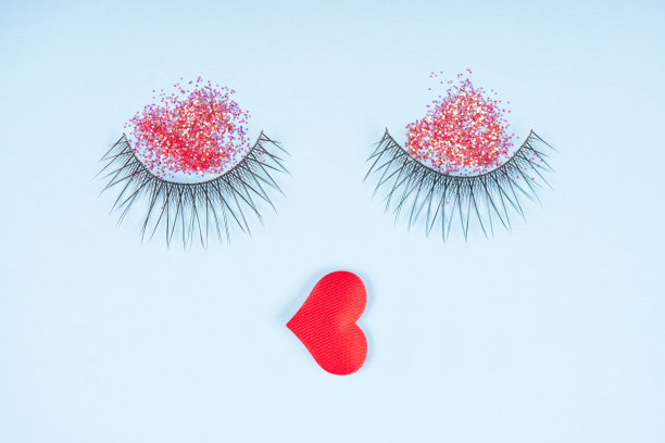 节日假期化妆。睫毛与红色闪光的眼影和rep嘴唇在柔和的蓝色背景。创意化妆美容理念图片下载