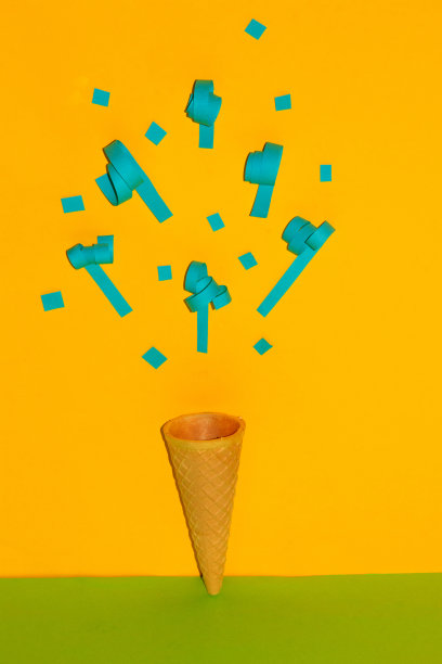 蓝色的五彩纸屑从冰淇淋区点燃，创意夏季派对概念，夏季热带度假，黄色背景图片下载
