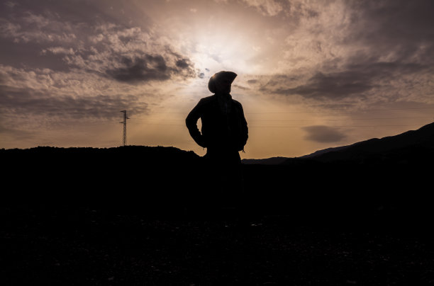 一个戴着牛仔帽的成年男子的剪影，站在沙漠中，映衬着天空。西班牙阿尔梅里亚图片下载
