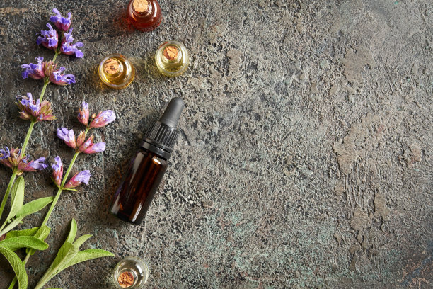 用新鲜鼠尾草叶和花在灰色背景的精油瓶图片下载