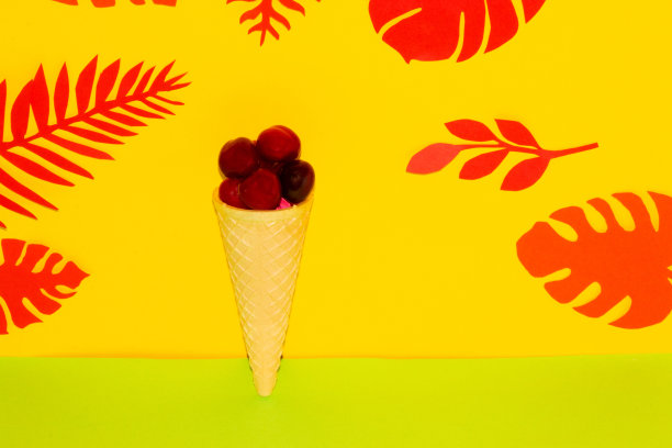 黄绿色背景上的圆锥体樱桃，创意夏日健康设计，冰淇淋健康，丛林树叶图片下载