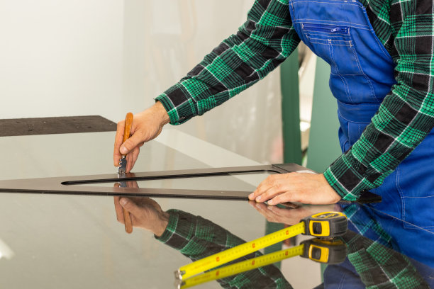 切割玻璃，玻璃车间，手工切割玻璃面板的尺寸，工作中的玻璃机图片下载