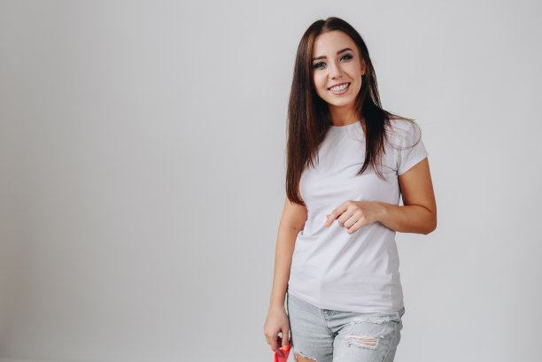 身穿白色t恤的快乐微笑的女孩自由地站在右侧的白色背景上图片下载