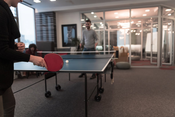 两个年轻的创业企业家在现代创意办公空间打乒乓球，背景是开会和头脑风暴图片下载