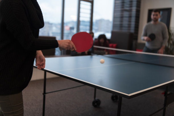 两个年轻的创业企业家在现代创意办公空间打乒乓球，背景是开会和头脑风暴图片下载