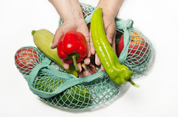 女人将蔬菜和水果放入可重复使用的蓝色网状袋中。棉质购物袋 - 零浪费图片下载