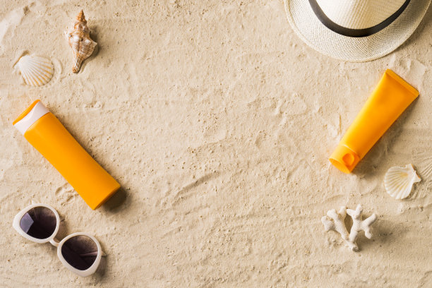 在夏天的沙滩上使用防晒霜、太阳镜和帽子图片下载