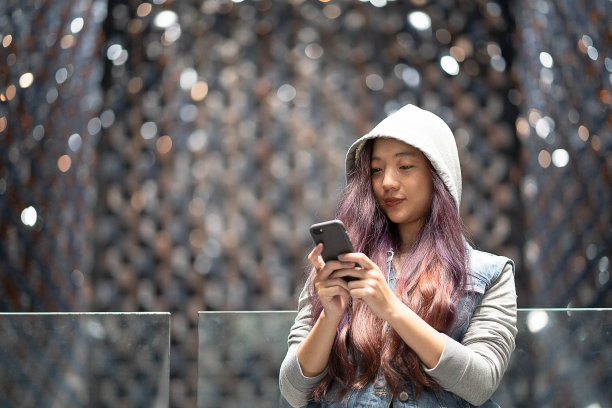 年轻的亚洲女性在商场玩智能手机图片下载