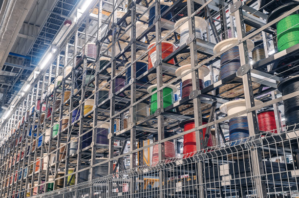 彩色电缆绕在线轴上。工厂的金属架子上有彩色线轴。图片下载