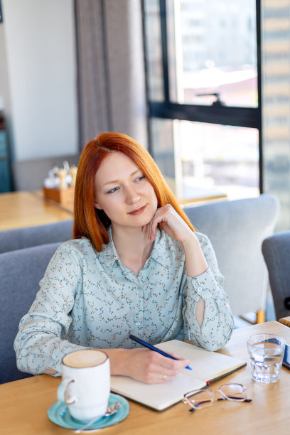 商务年轻女子坐在咖啡馆的一张桌子旁图片下载