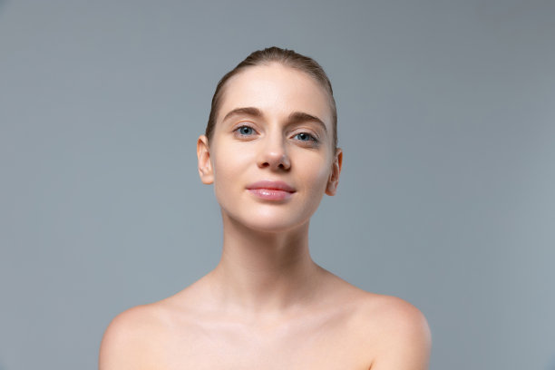 年轻美丽的女孩的肖像没有化妆的脸看着相机，摆孤立的灰色工作室背景图片下载
