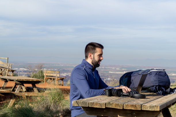 数码游牧民在阳光明媚的日子里用笔记本电脑在大自然中工作图片下载