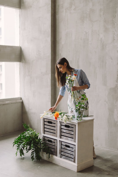 花店工作区:年轻漂亮的白人女性正在制作花卉装饰品，她手里拿着一束花。图片下载