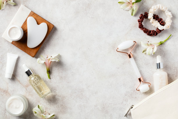 含天然化妆品的化妆袋，用于面部皮肤护理。石桌上挂沙、白玉面辊、精华液、保湿霜。平铺，俯视图。图片下载