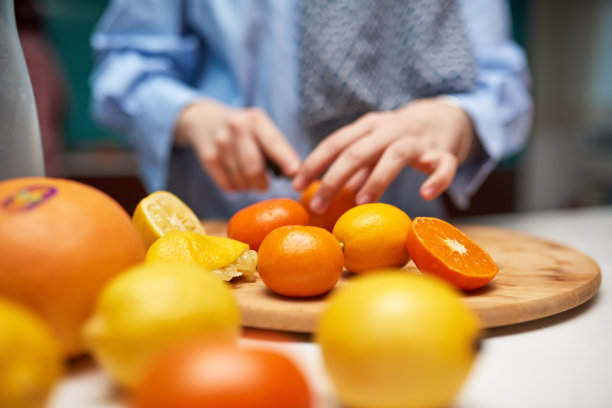 一张特写照片，一名妇女的手正在切割和准备水果，以制作健康的奶昔。健康生活方式的概念图片下载