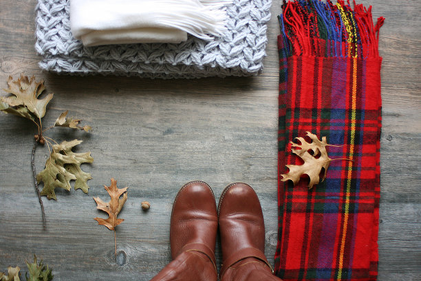 女性秋季寒冷天气的服装，靴子，围巾和个人饰品平放在质朴的木头背景上，树叶从上面直接拍摄，复制空间图片下载