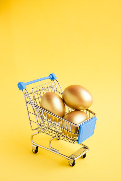 购物车与三个金鸡蛋孤立在黄色背景。垂直的照片。图片下载