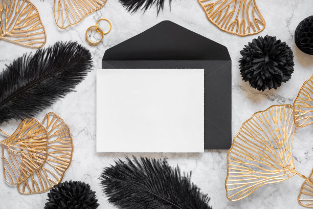 空白卡片和信封靠近黑色羽毛和金色叶子，上面有结婚戒指图片下载