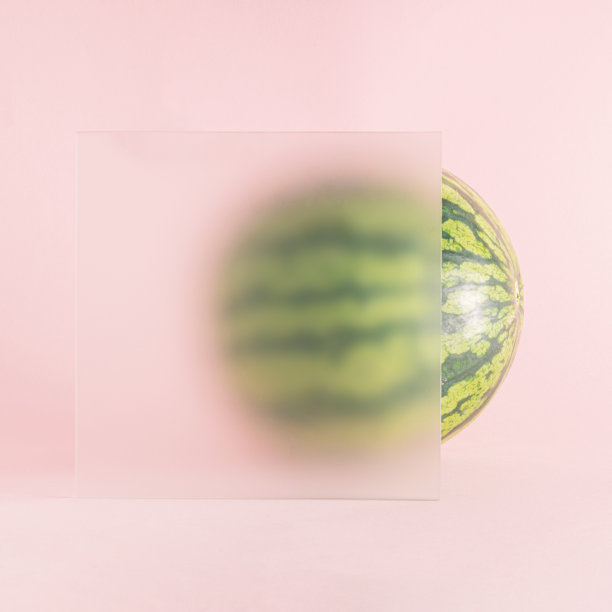 这个创意是用西瓜做成的，部分放在磨砂玻璃后面，背景是粉色。最小复制空间概念。夏季水果的灵感。图片下载