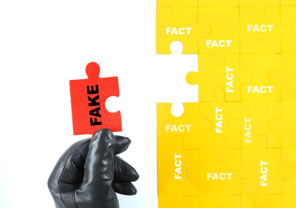 一只戴着黑色手套的手拿着一个红色的谜题，旁边是一组黄色的谜题——事实。在媒体中替代事实的概念。图片下载